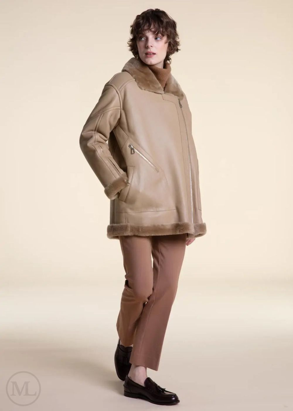 Women wearing a shearling leather coat with fur trim on a beige background
