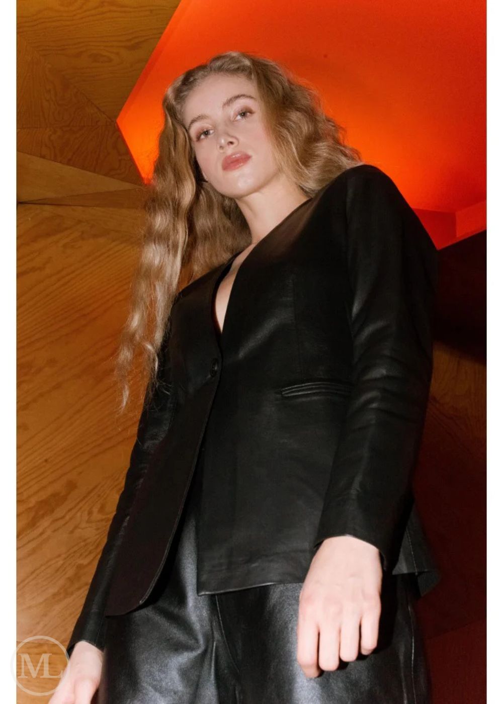 Woman Wearing a Black Leather Blazer standing against a wooden wall with red accents