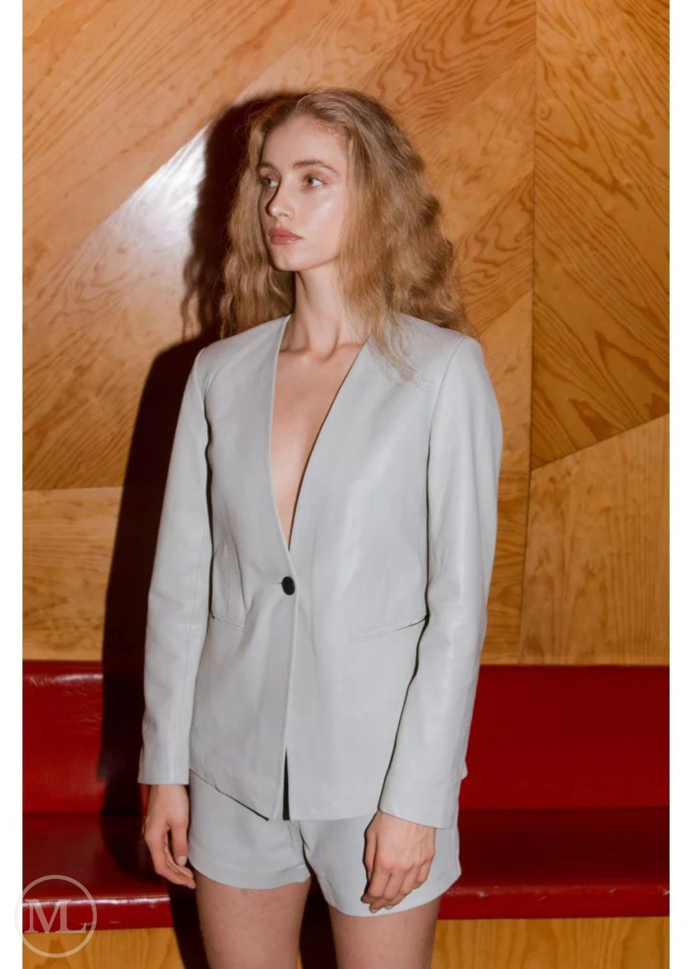 Woman wearing a Lvory Leather Blazer Coat against a wooden wall.