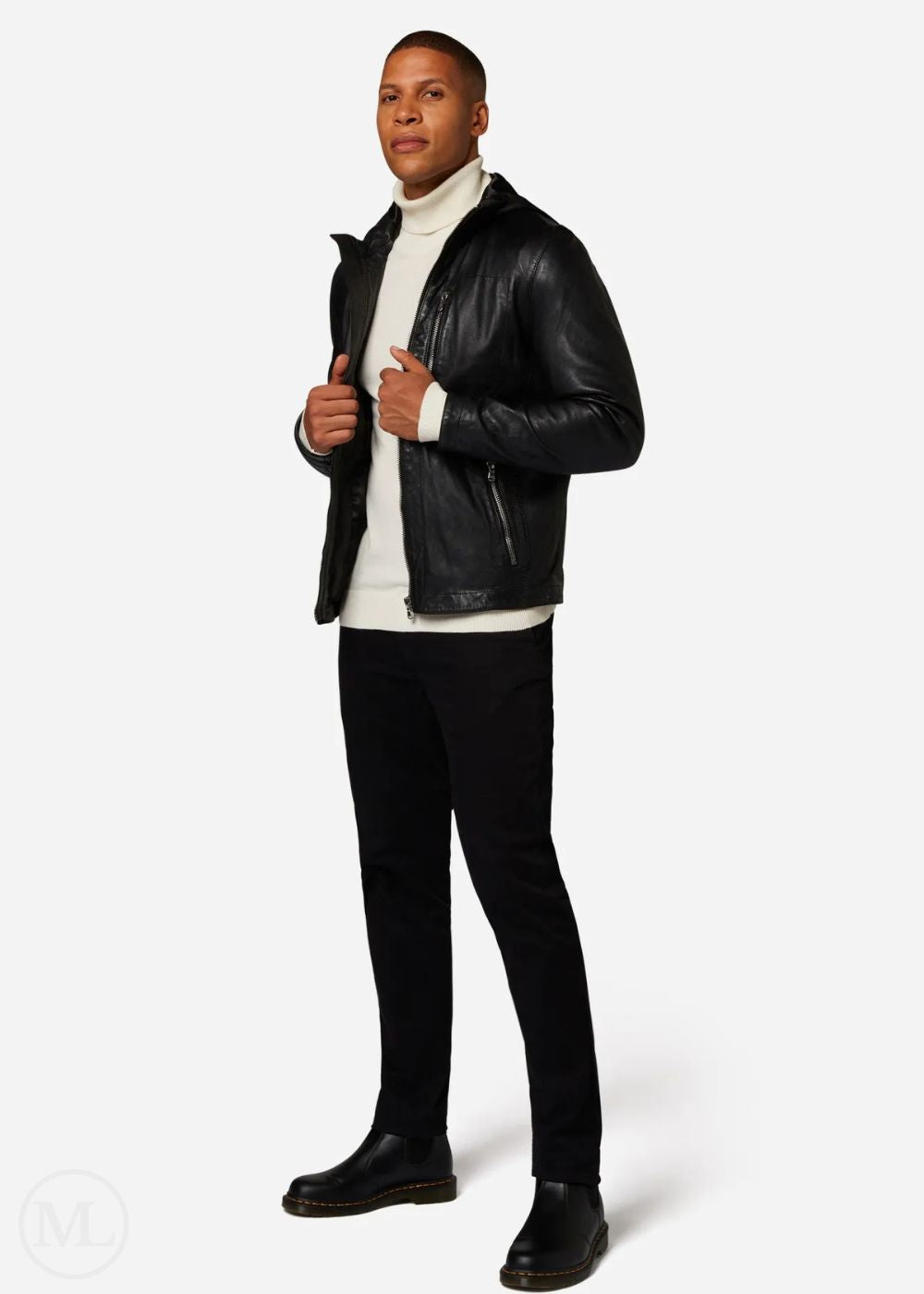 Man wearing a black leather jacket, white turtleneck, black pants, and black shoes on a white background
