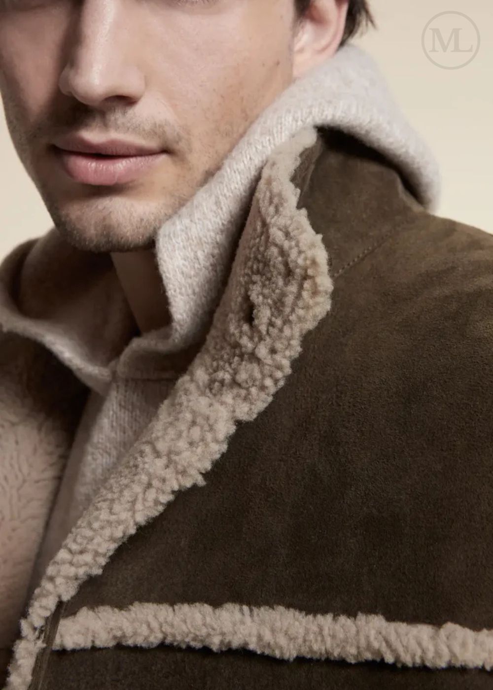 Close-up of a brown suede leather coat with beige sherpa lining on a beige background