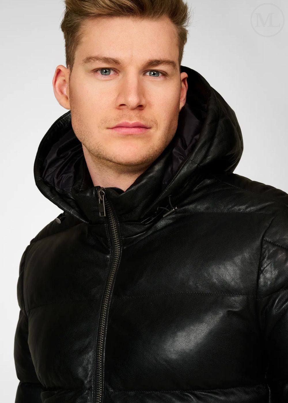 Man wearing a black leather puffer jacket against a white background