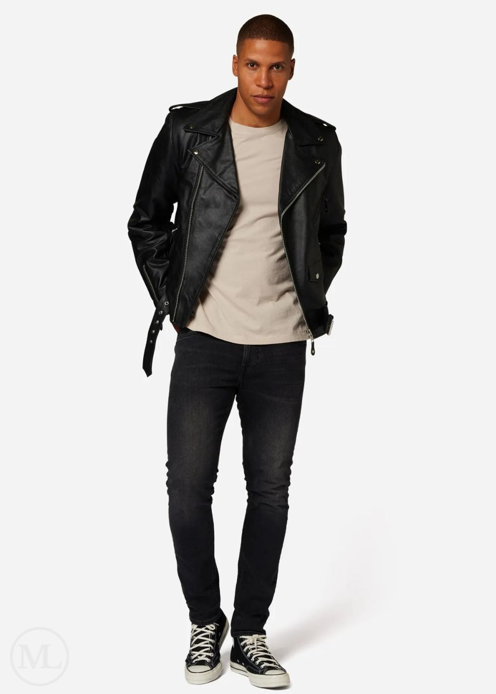 Man wearing a black leather biker jacket, beige shirt, and black jeans on a white background
