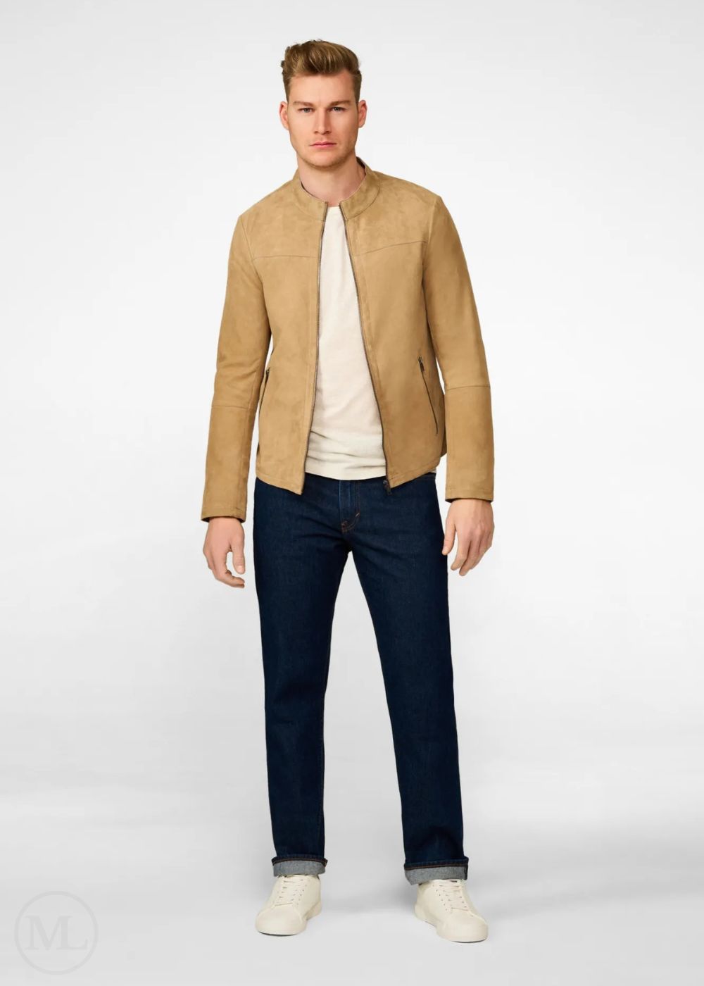 Man wearing a beige suede leather jacket, white shirt, dark jeans, and white shoes on a white background
