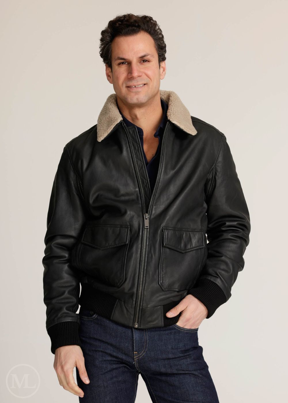 Man wearing a black leather bomber jacket with beige lining on a plain background