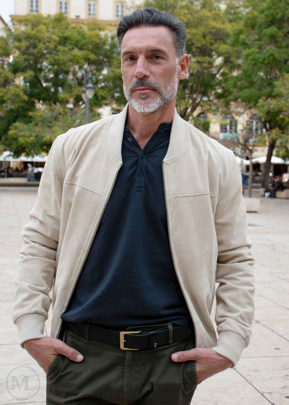 Man wearing a Ivory suede jacket over a dark shirt with a blurred background