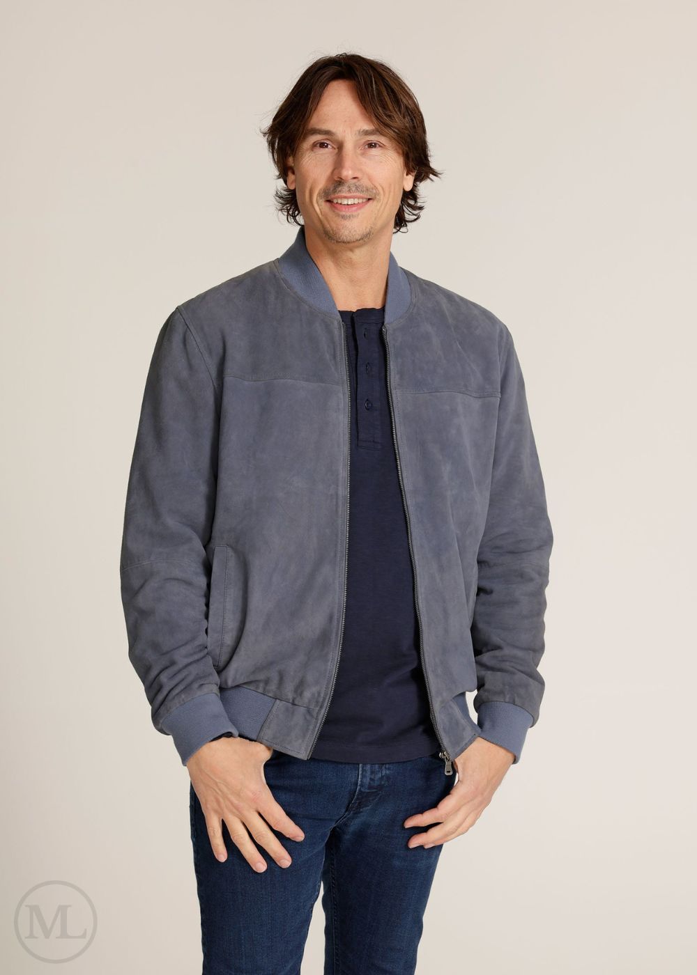 Man wearing a Navy suede jacket over a navy shirt on a beige background