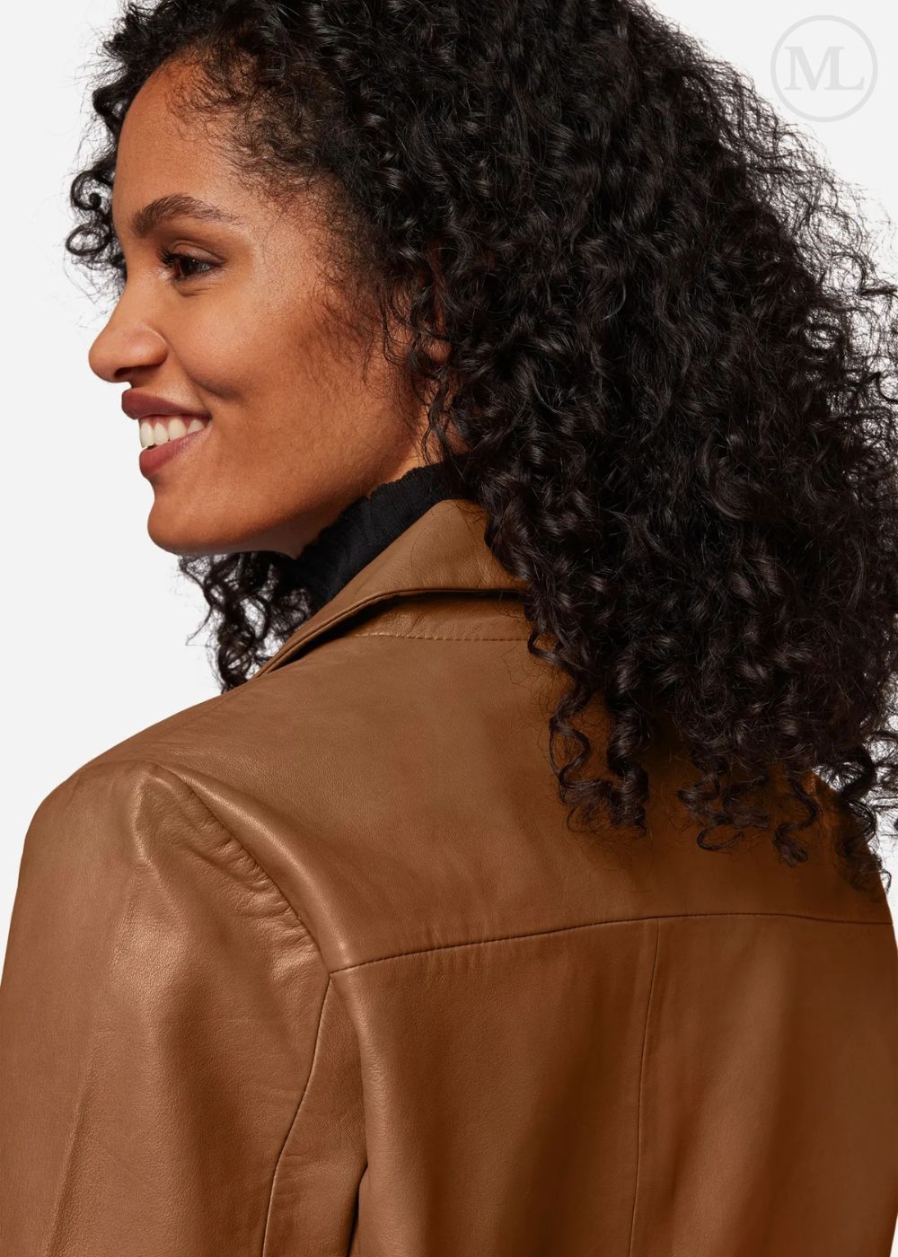 Woman wearing a brown leather cropped jacket with a neutral background