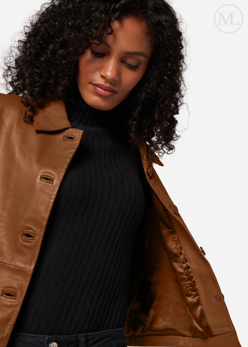 Woman wearing a brown leather cropped jacket over a black turtleneck on a white background