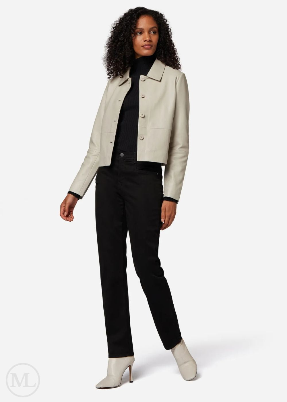 Woman wearing a lvory leather cropped jacket, black top, and black pants on a white background