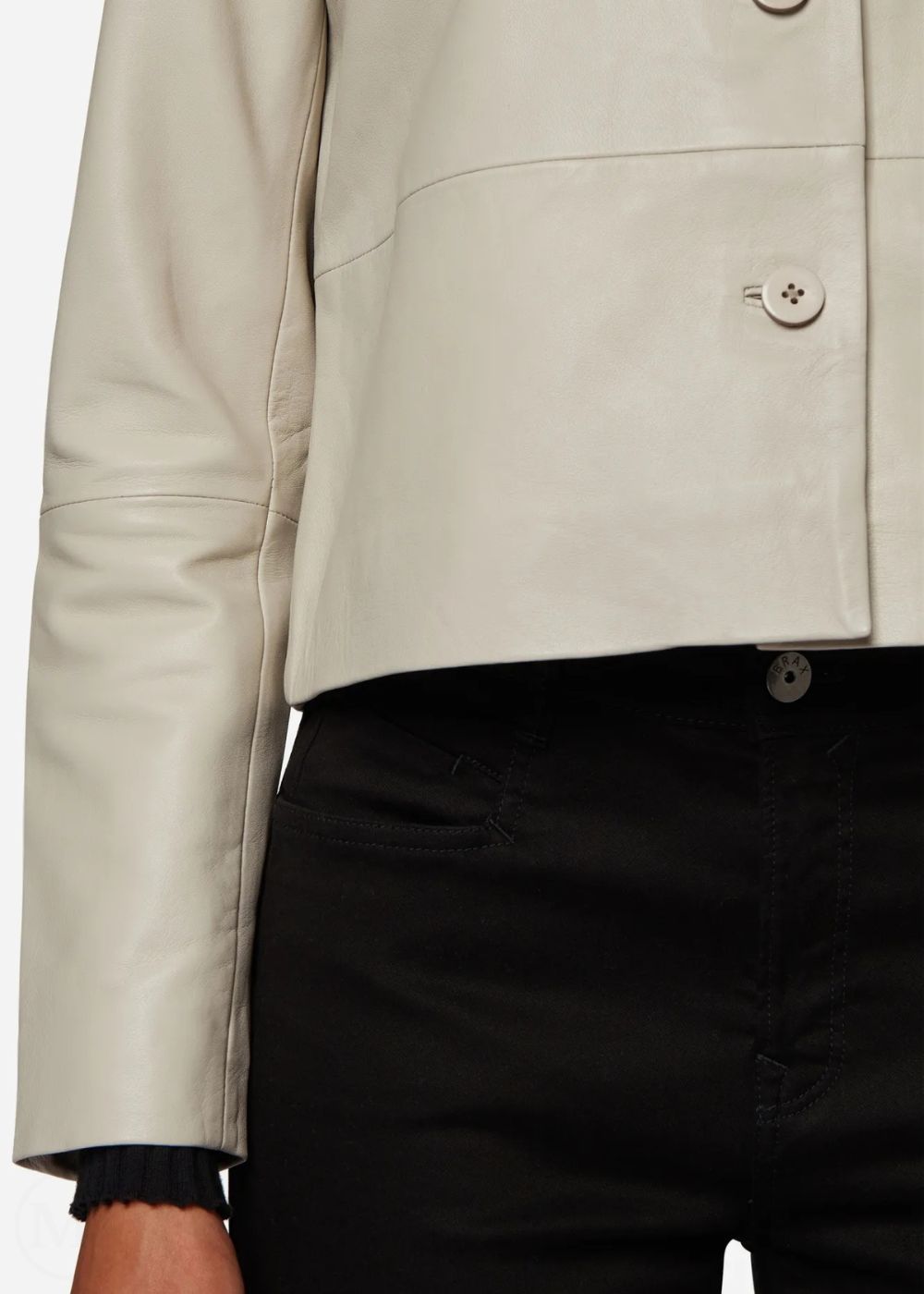 Close-up of a lvory leather cropped jacket with black pants on a white background