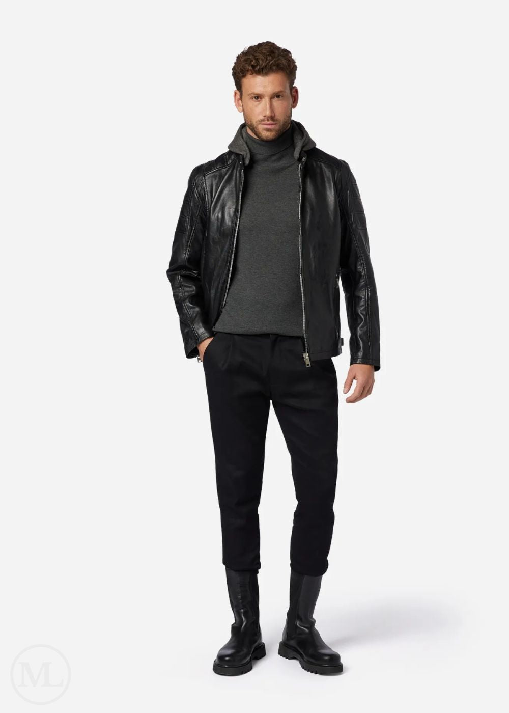 Man wearing a black leather jacket, gray sweater, black pants, and black shoes on a white background