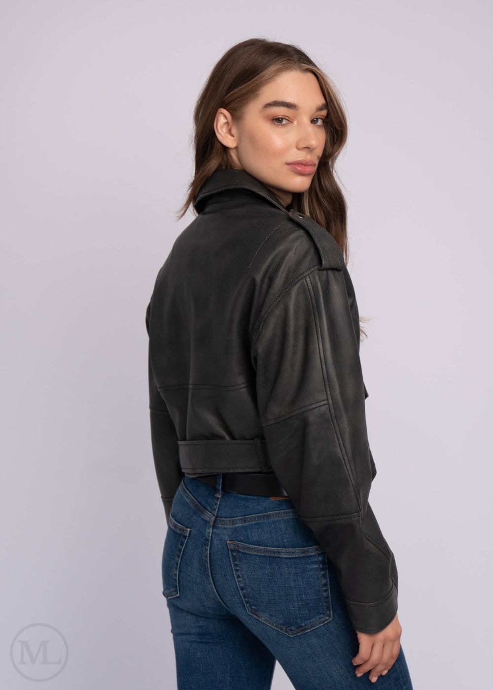 Femme portant une veste en cuir noire et un jean bleu sur fond blanc