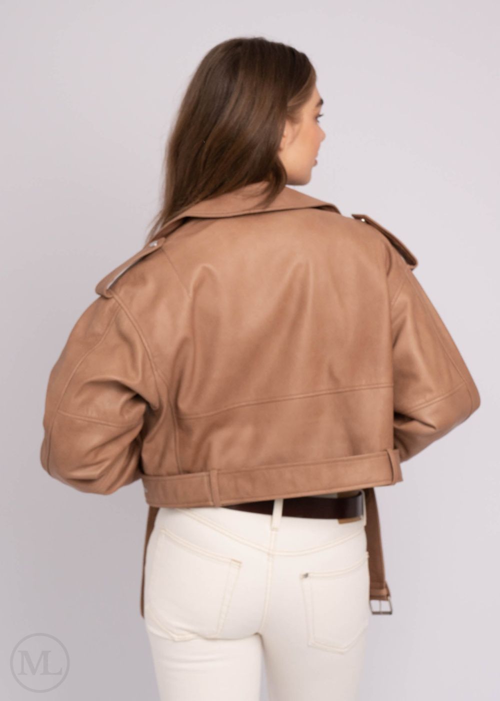 Woman wearing a taupe leather jacket on a plain background