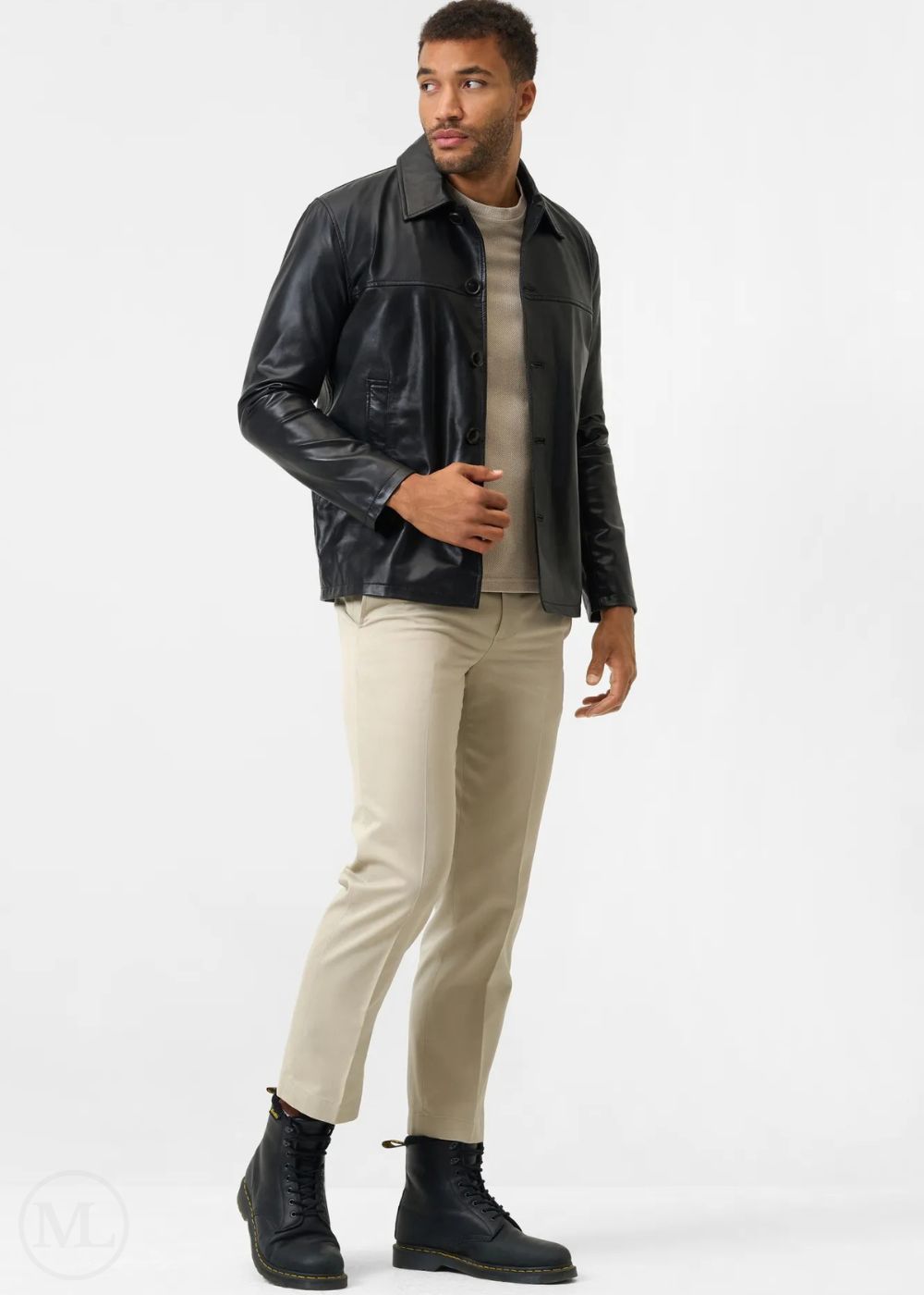 Man wearing a black leather coat, beige pants, and black boots on a white background