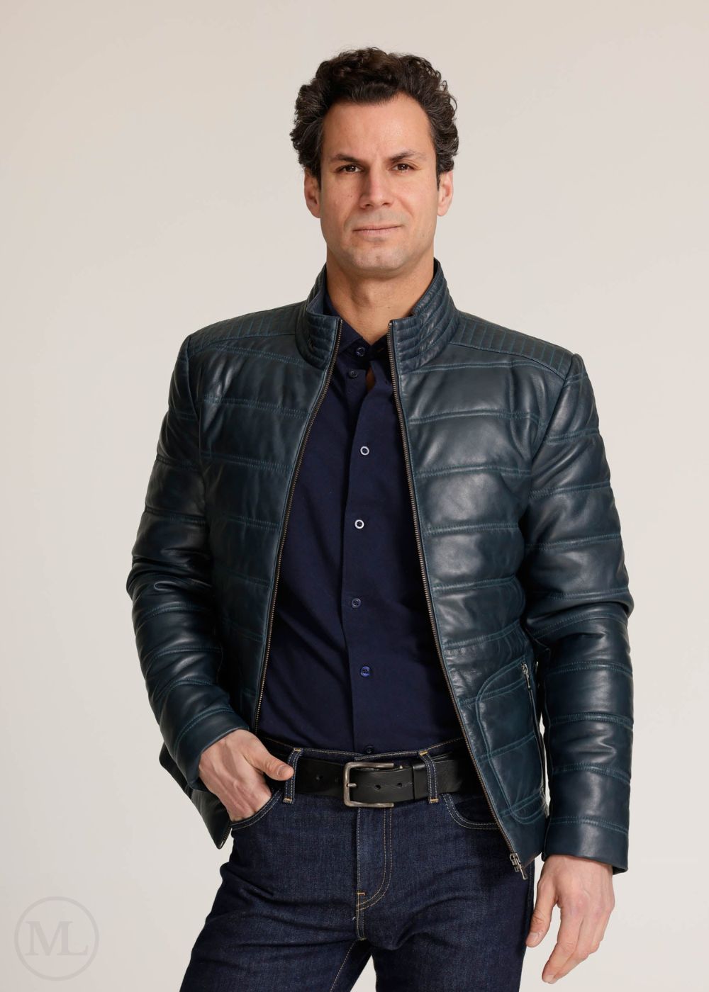 Man wearing a navy leather jacket and dark jeans against a plain background