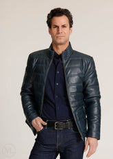 Man wearing a navy leather jacket and dark jeans against a plain background