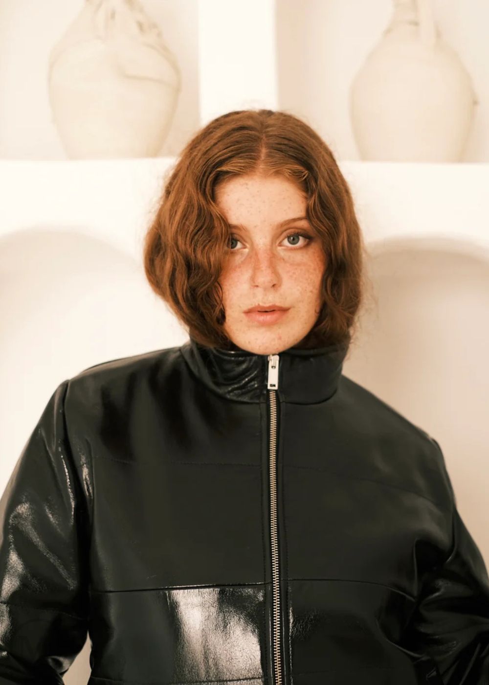 Women wearing a black leather Puffer jacket in front of white abstract art