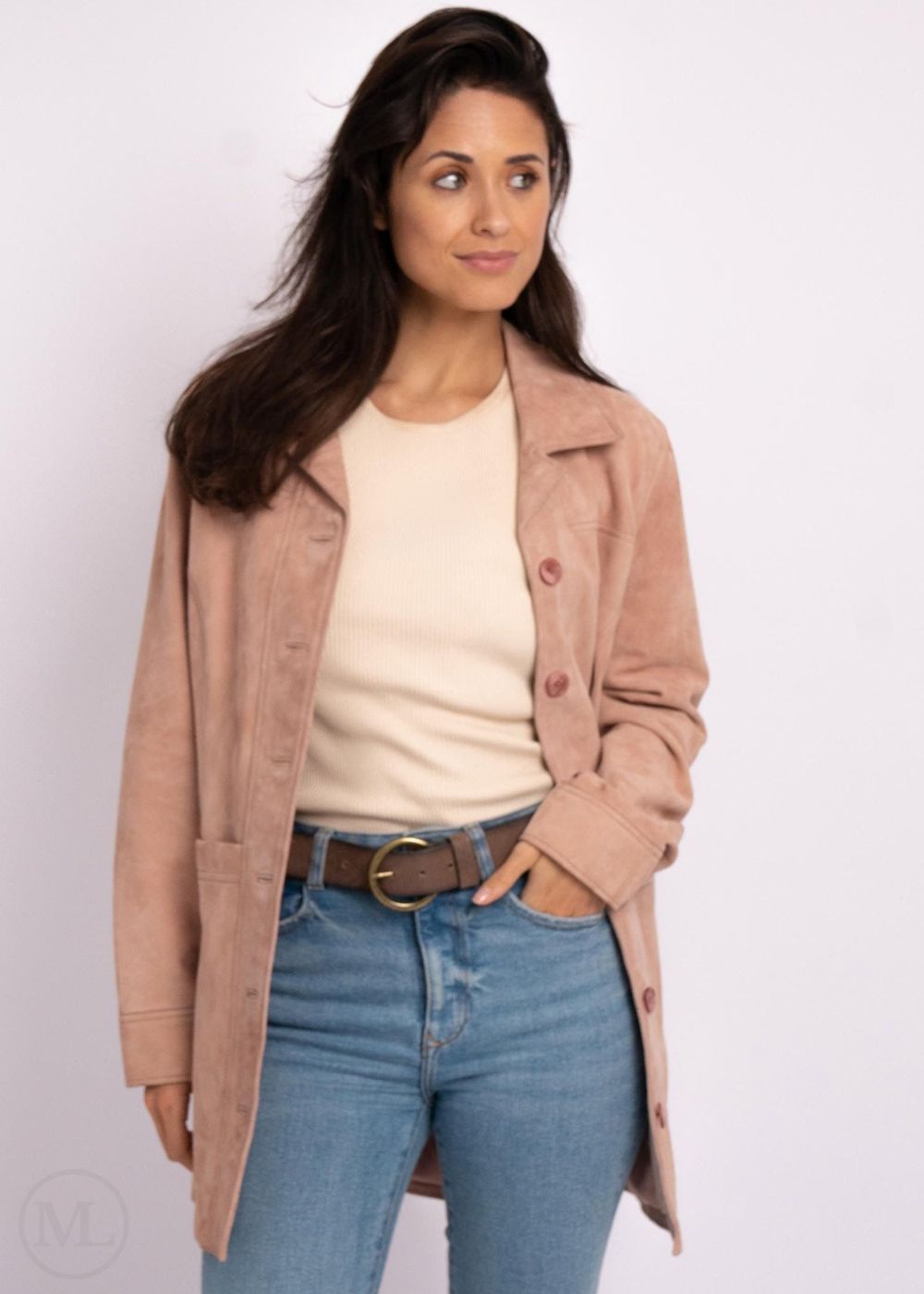 Woman wearing a pink leather coat, white shirt, and blue jeans on a light pink background
