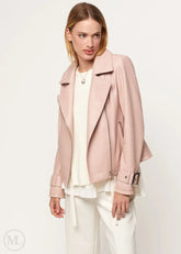 Woman wearing a fuschia leather biker jacket over a white outfit on a plain background