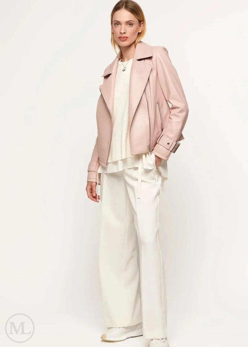 Woman wearing a fuschia leather biker jacket and white pants on a white background