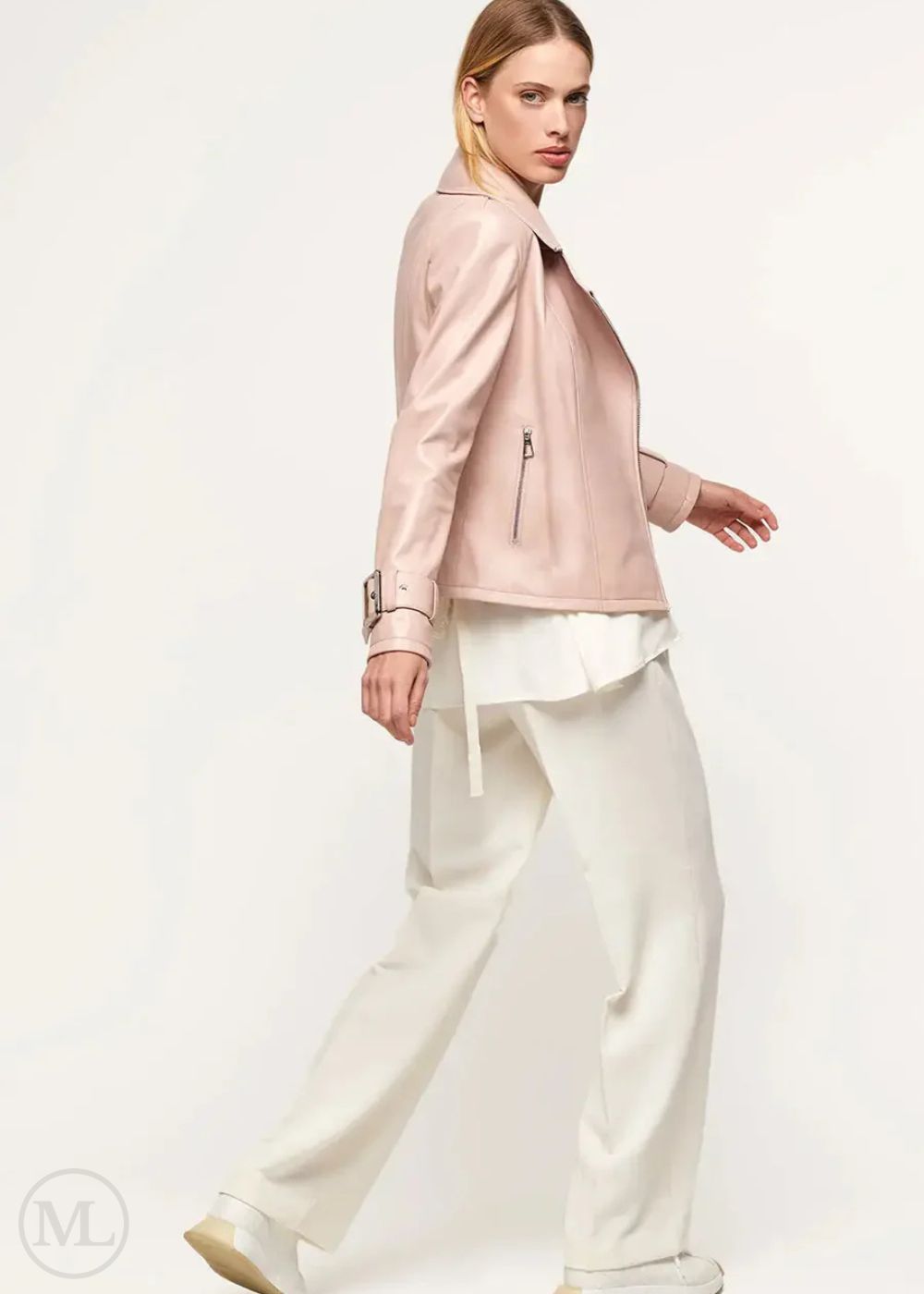 Woman wearing a fuschia leather biker jacket and white pants on a white background