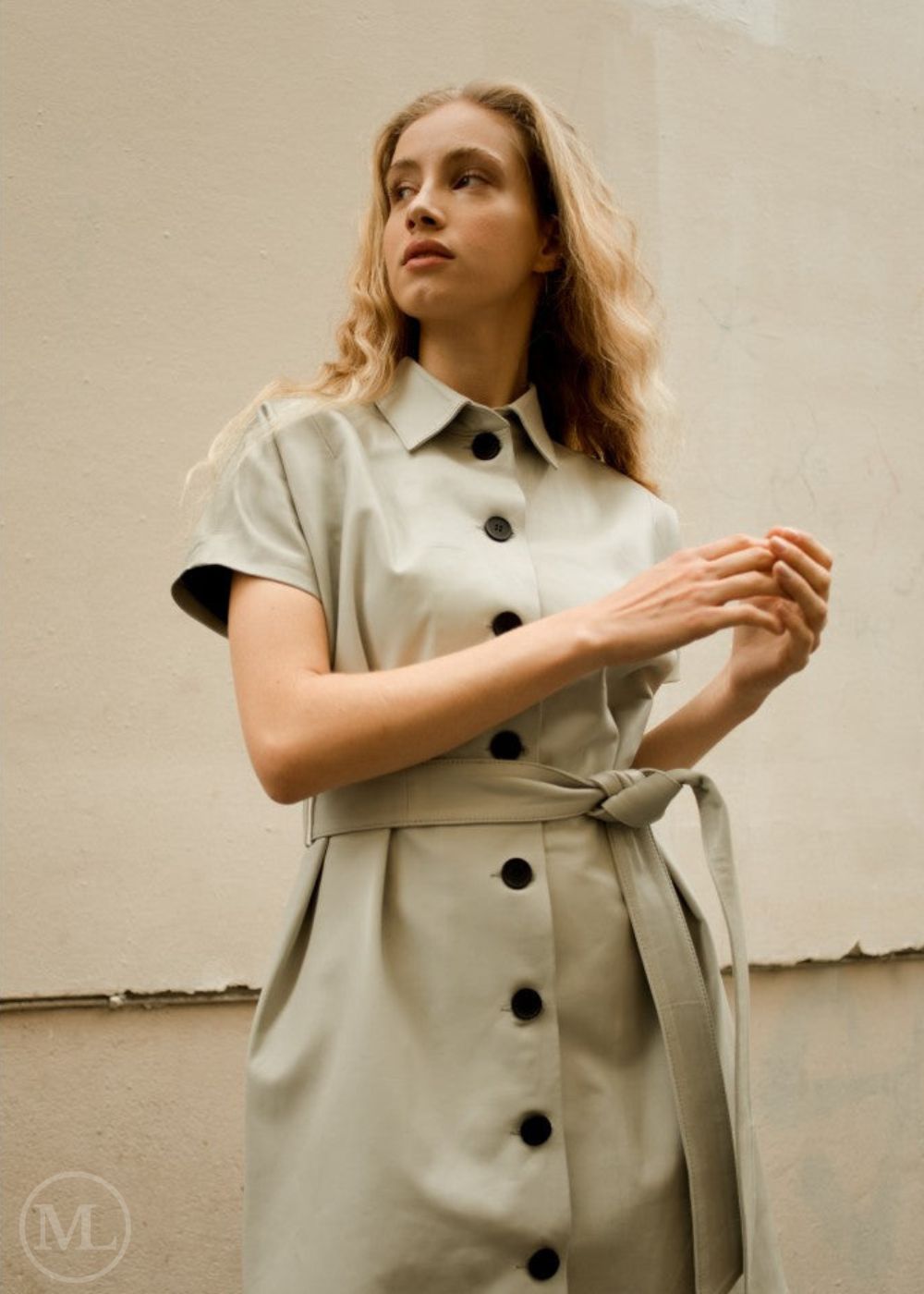 Femme portant une robe en cuir véritable beige avec des boutons noirs sur un fond uni