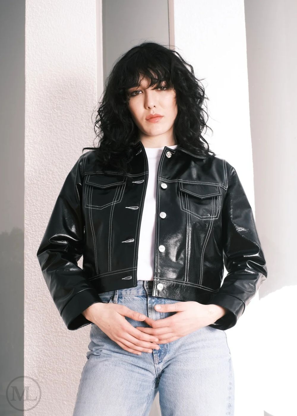Women wearing a Cropped black leather Trucker jacket and light blue jeans against a neutral background
