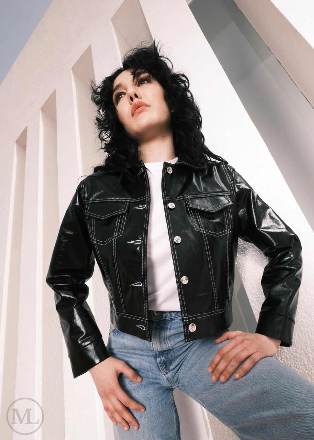 Women wearing a Cropped black leather Trucker jacket and light blue jeans against a neutral background
