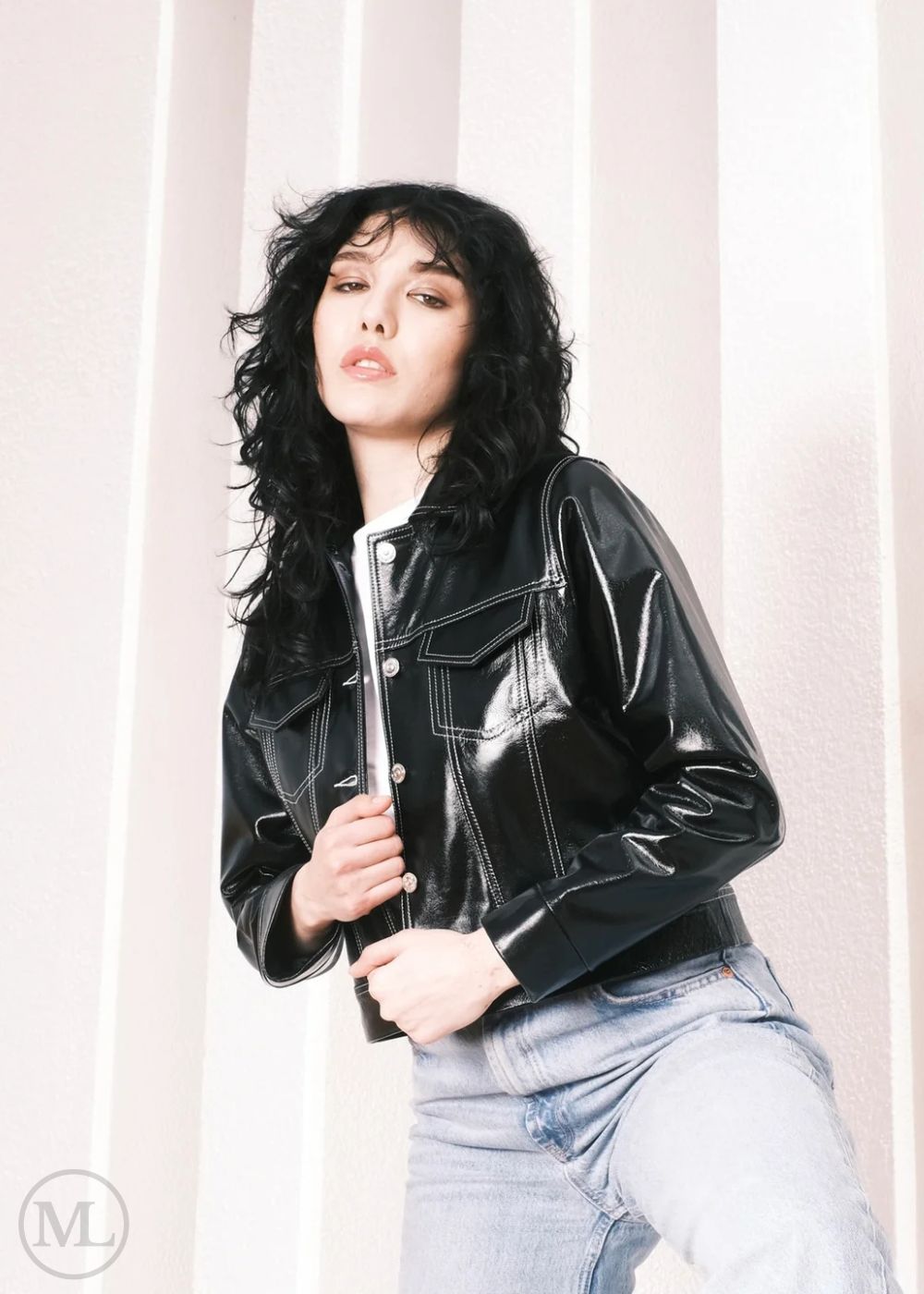 Women wearing a Cropped black leather Trucker jacket and light blue jeans against a neutral background