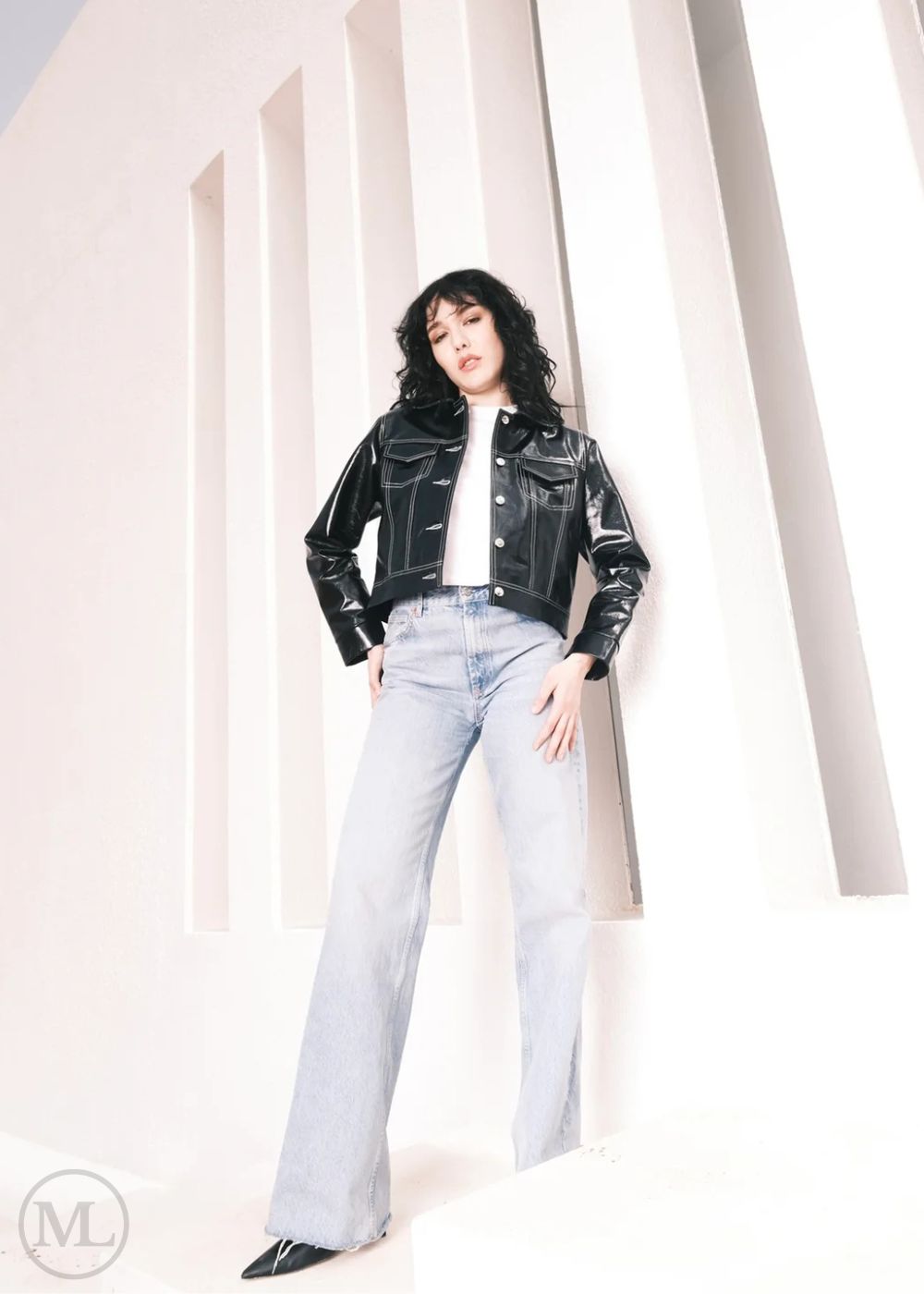 Women wearing a Cropped black leather Trucker jacket and light blue jeans against a neutral background