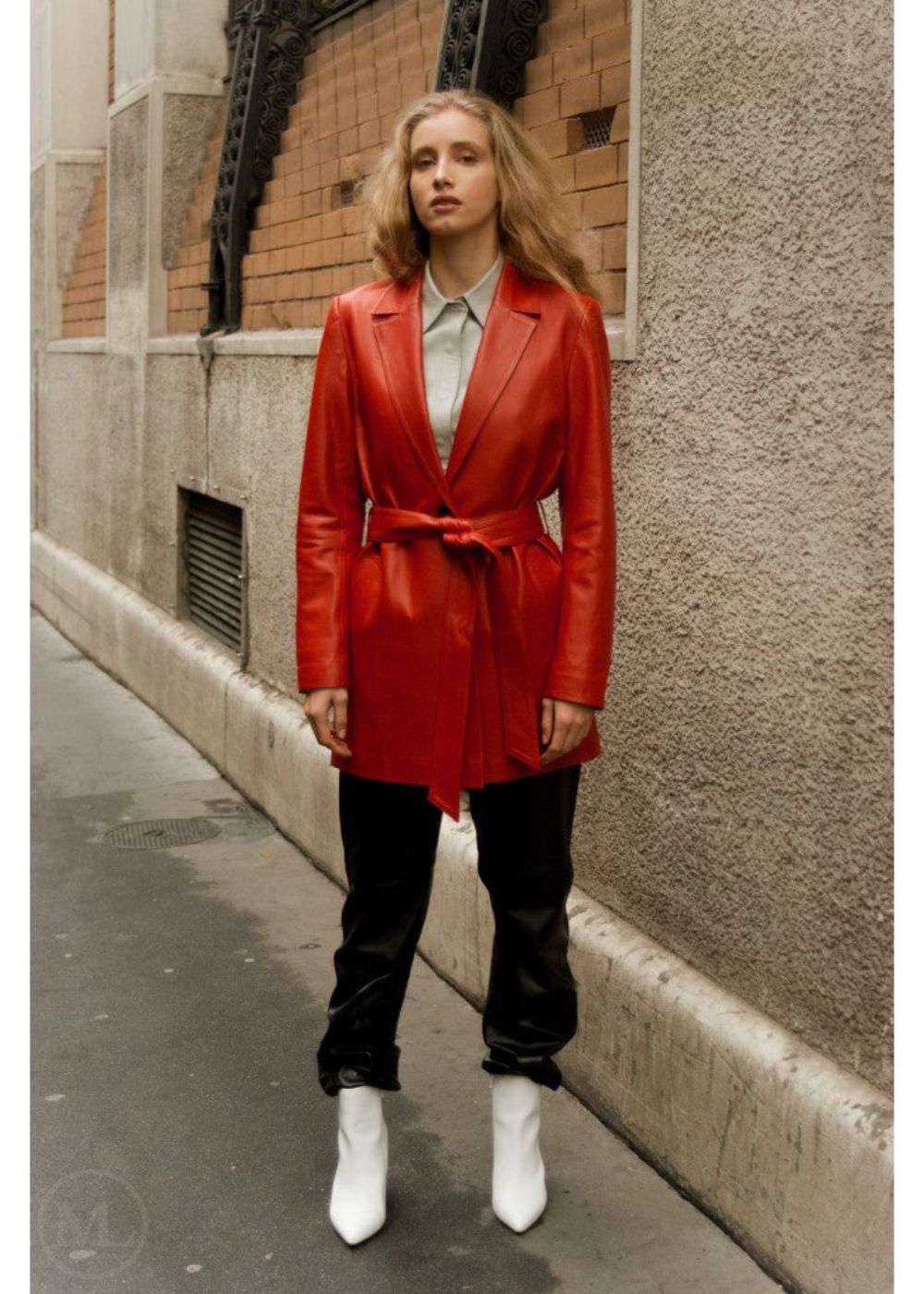 Woman wearing a red leather blazer coat standing on a city street.