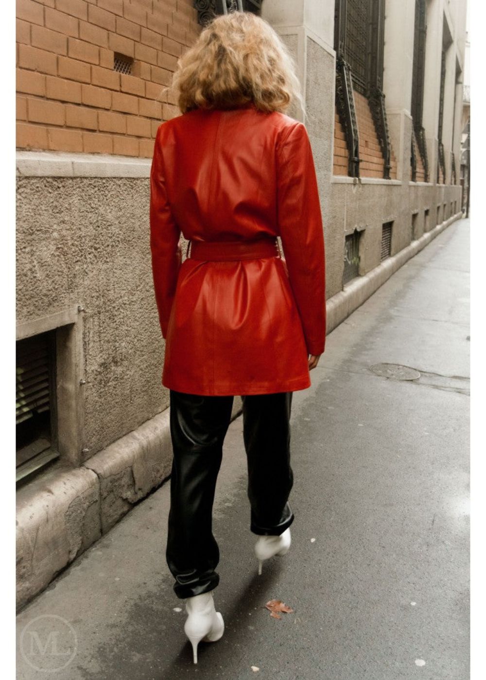 Woman wearing a red leather blazer coat walking down a city street.