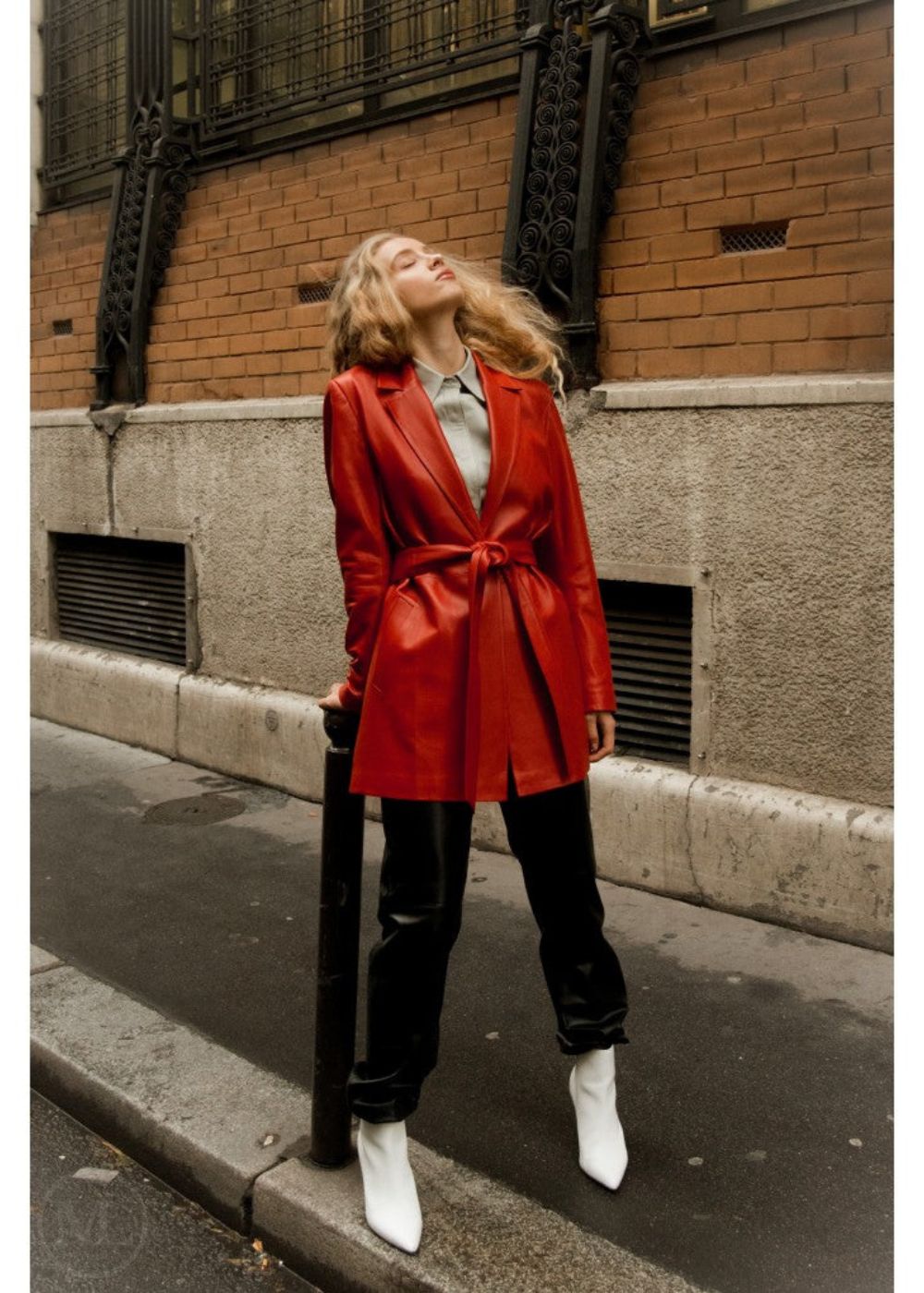 Woman in a red leather blazer coat standing on a city street