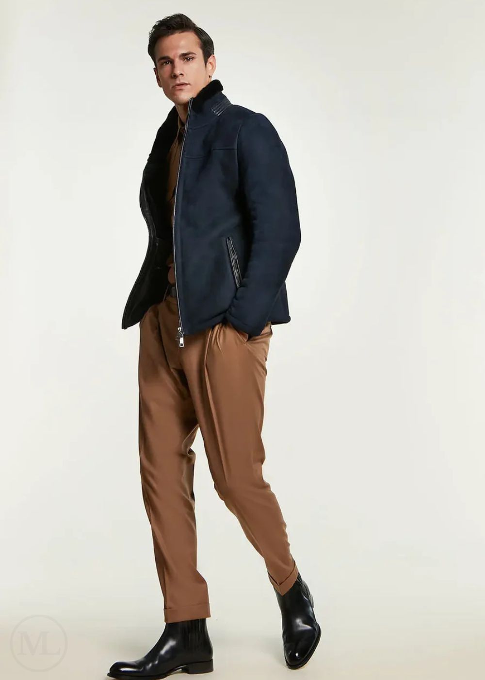 Man wearing a navy blue jacket and brown pants on a white background