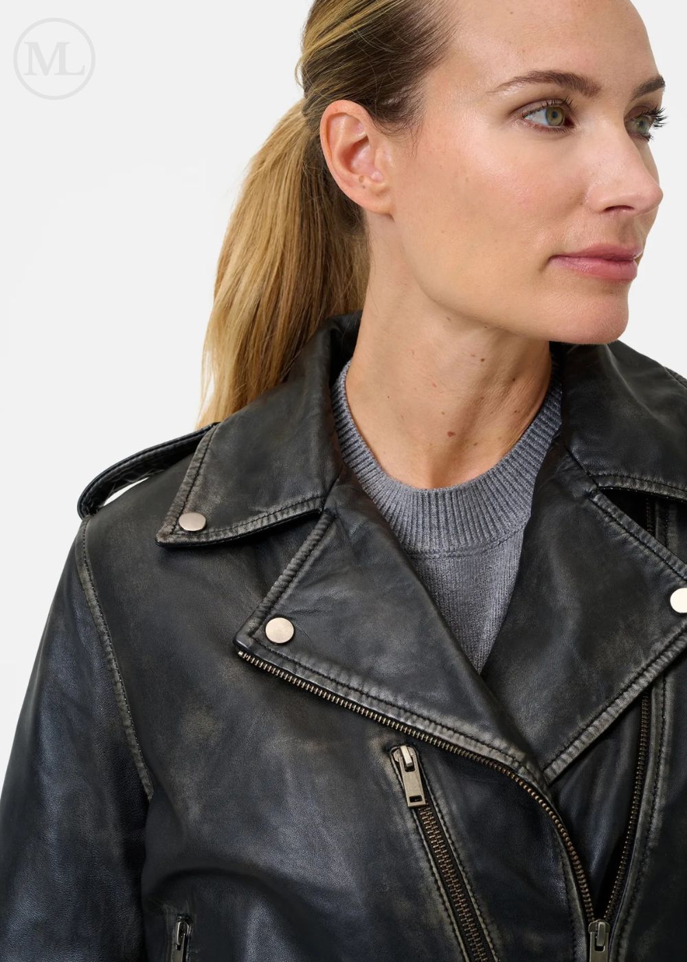 Woman wearing a black leather biker jacket with a neutral background