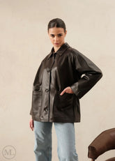 Woman wearing a dark brown leather trucker jacket against a beige background