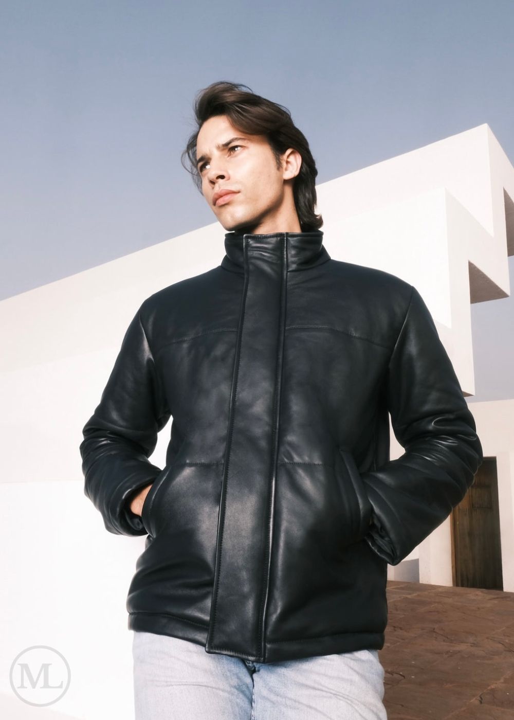 men wearing a black leather down jacket standing outdoors with a modern building in the background