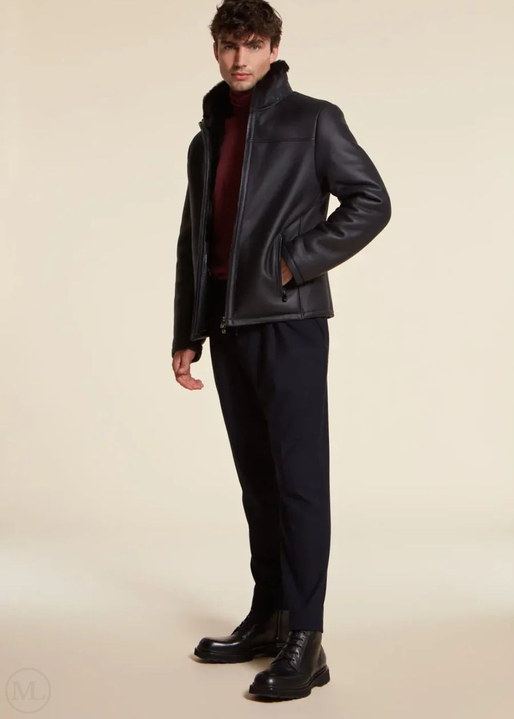 Man wearing a dark blue leather jacket and dark pants on a beige background