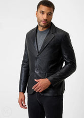 Man wearing a black leather blazer jacket over a gray shirt on a white background