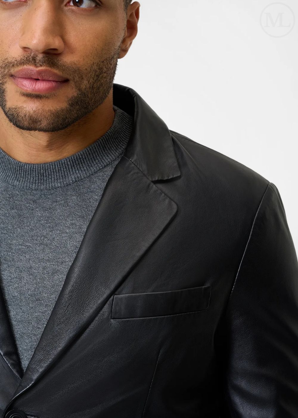 Man wearing a black leather blazer jacket over a gray sweater on a white background