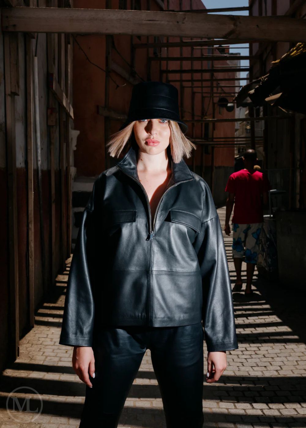 Women wearing a black leather jacket and hat in an urban setting
