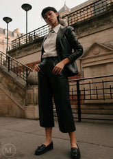 Women wearing a black leather Blazer jacket and black pants standing on a city street.