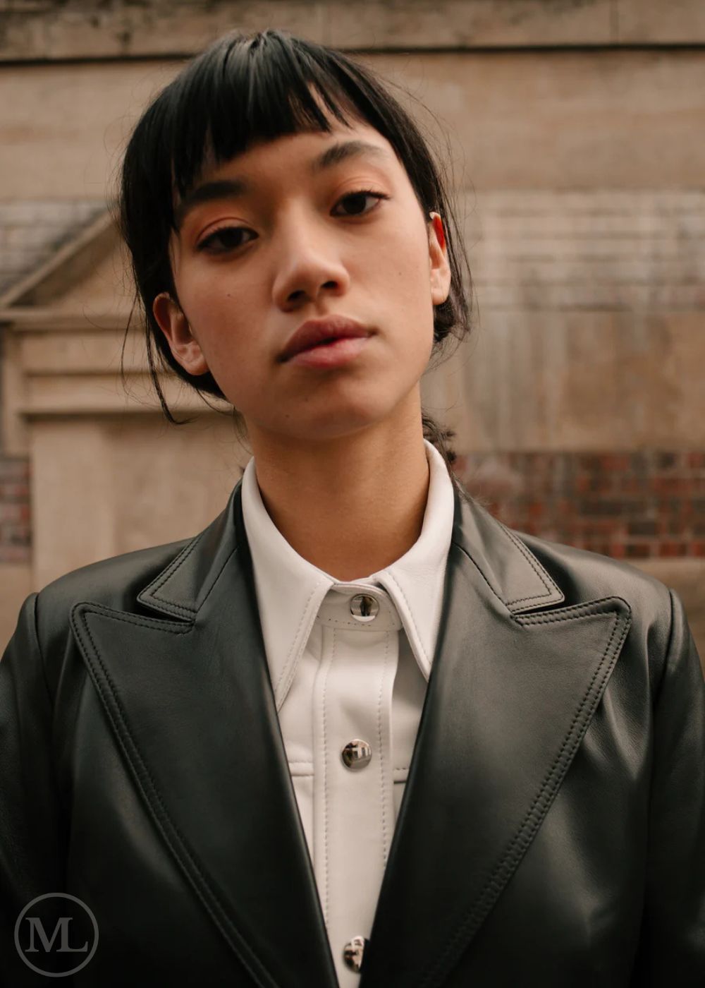 Women wearing a black leather Blazer jacket and black pants standing on a city street.