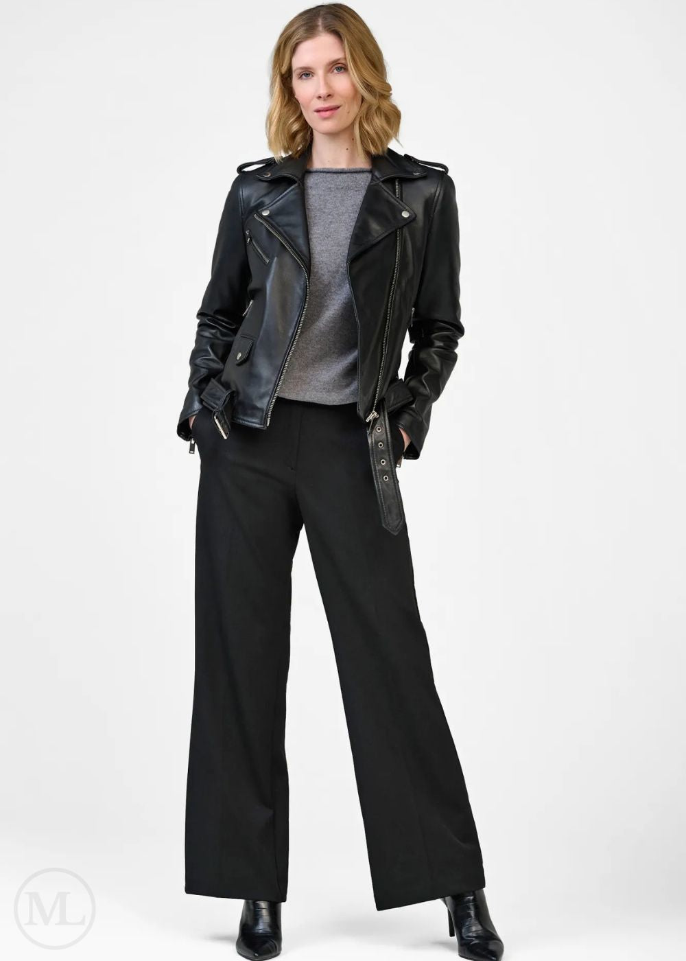 Woman wearing a black leather biker jacket and black pants on a white background
