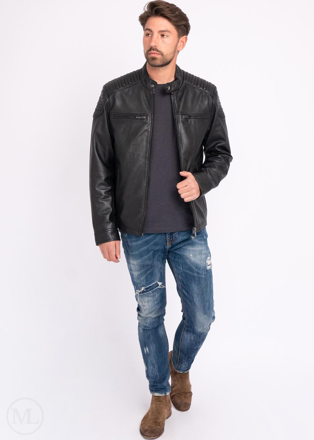 Man wearing a black leather jacket, dark shirt, blue jeans, and brown boots on a white background