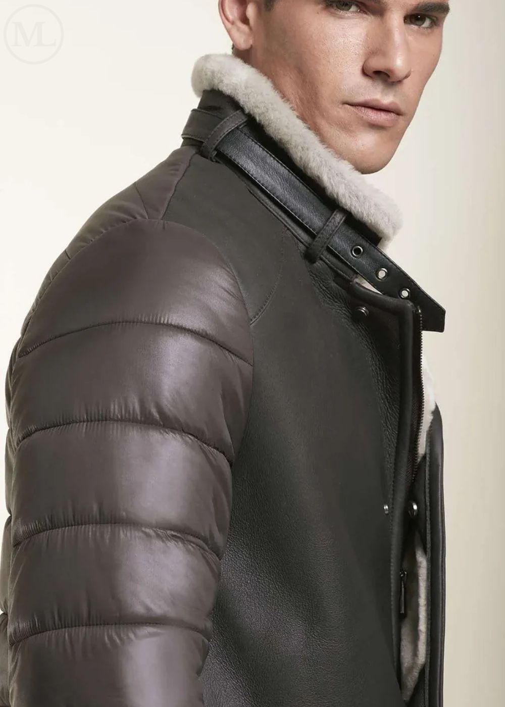 Man wearing a brown shearling jacket with a light-colored fur collar on a plain background