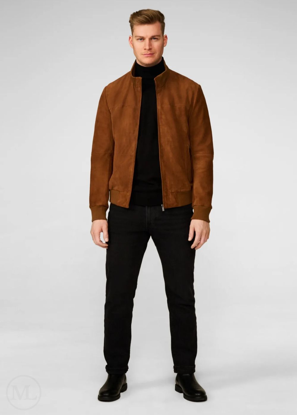 Man wearing a brown suede bomber jacket over a black turtleneck and black pants on a white background