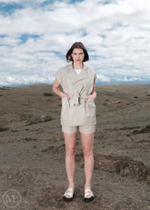 Woman in lvory leather vest outfit standing in a desert landscape with a cloudy sky.