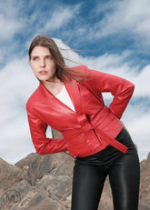 Woman wearing a red Leather Blazer jacket and black pants standing on rocky terrain with a blue sky.
